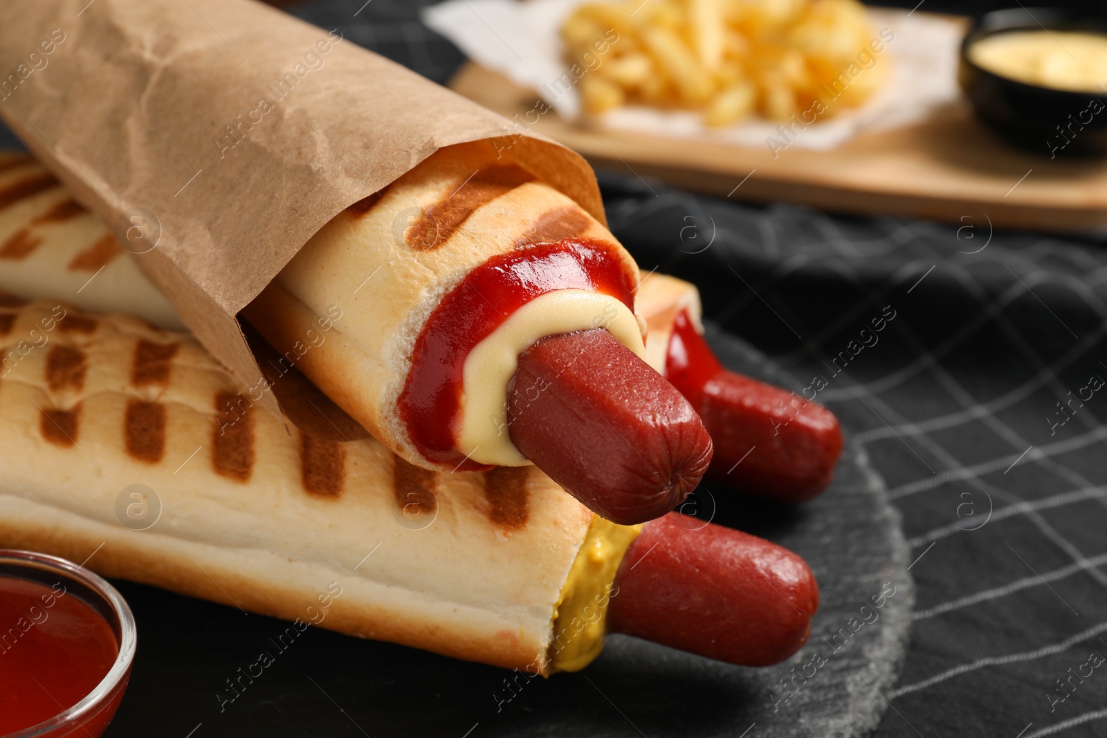 Photo of Delicious french hot dogs, fries and dip sauce on table, closeup