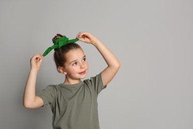 Cute little girl with stylish bandana on grey background, space for text