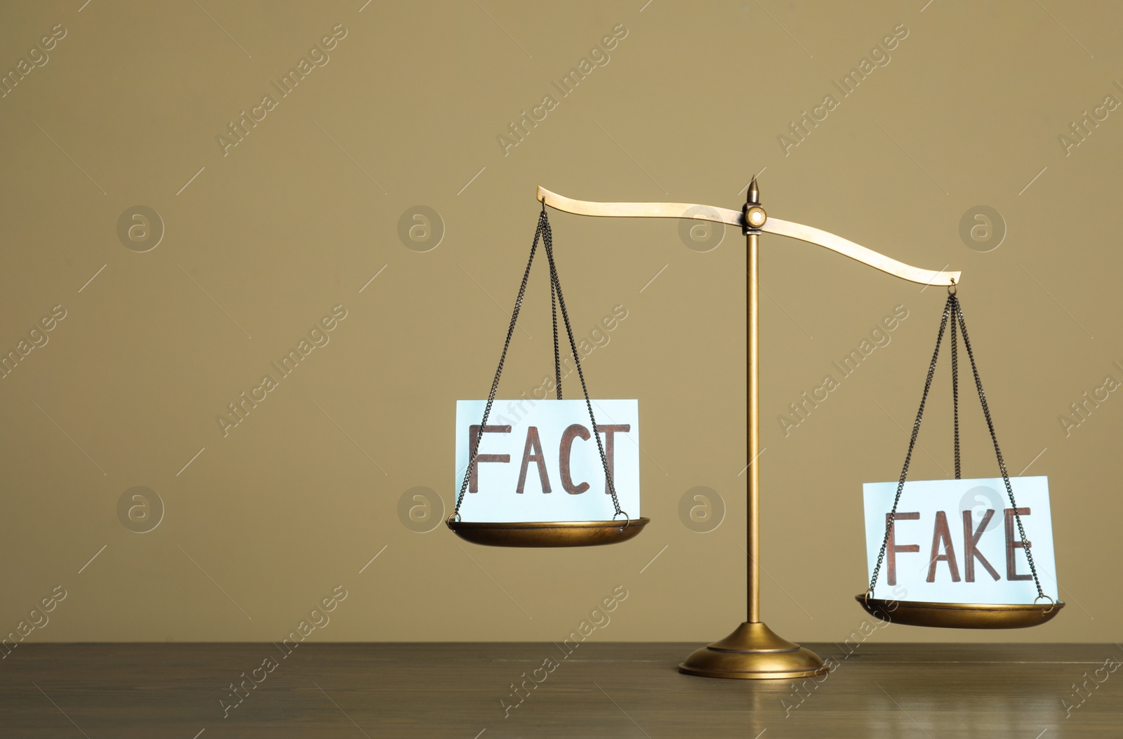 Photo of Scales with words FACT and FAKE on wooden table, space for text