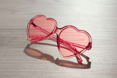 Photo of Stylish heart shaped sunglasses on wooden background