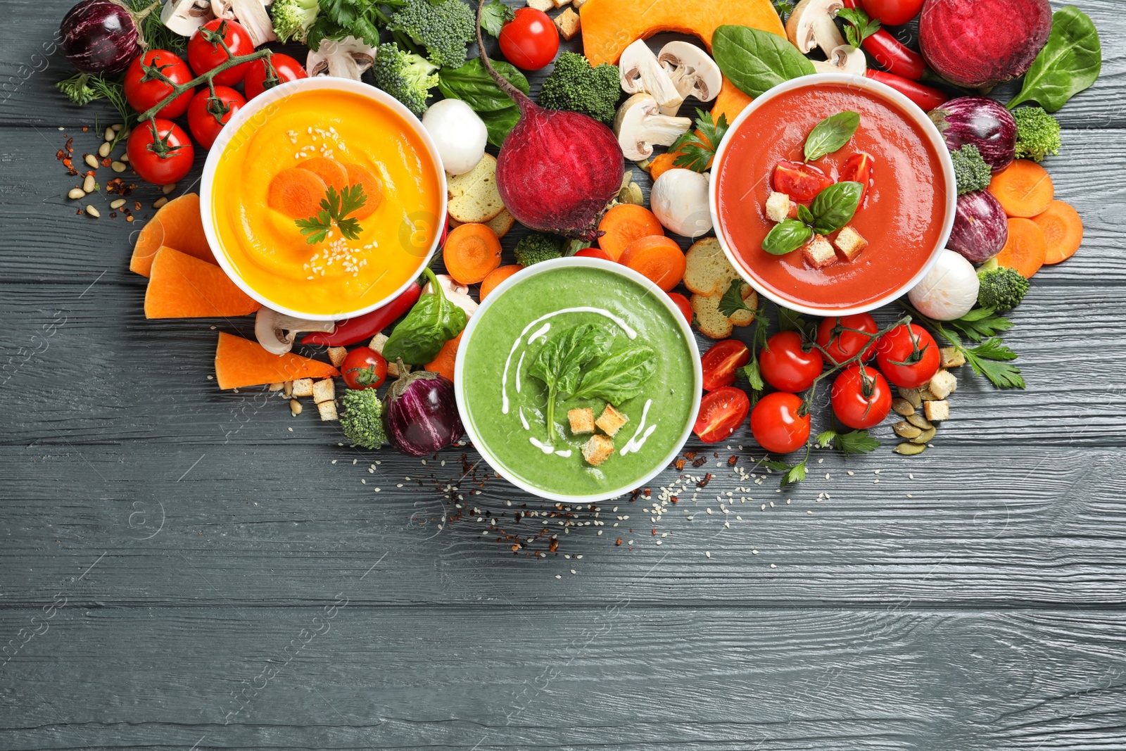 Photo of Various cream soups, ingredients and space for text on wooden background, flat lay. Healthy food