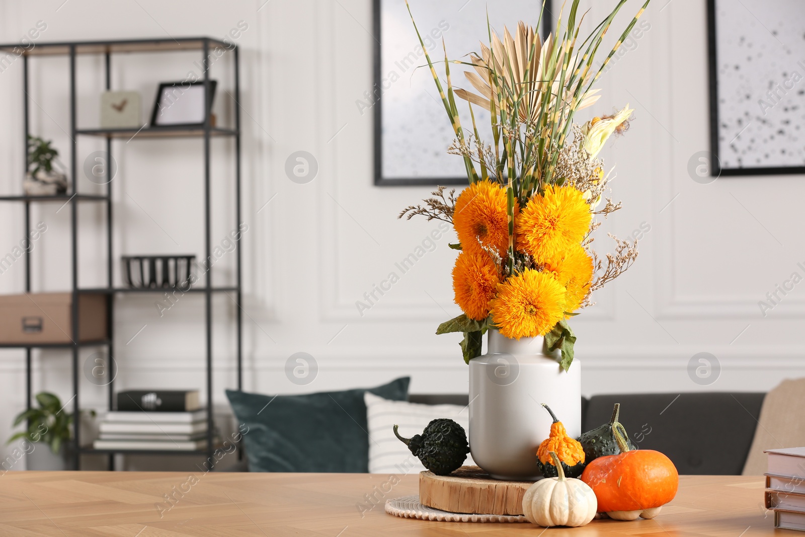 Photo of Beautiful autumn bouquet and pumpkins on wooden table indoors