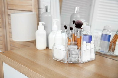 Photo of Organizer with cosmetic products on wooden table in bathroom