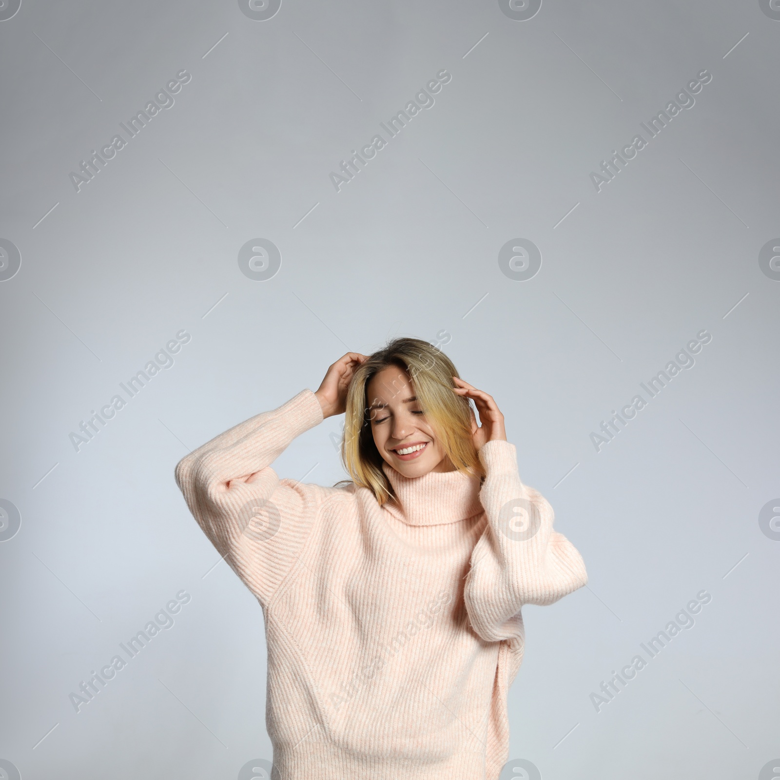 Photo of Beautiful young woman wearing knitted sweater on light grey background