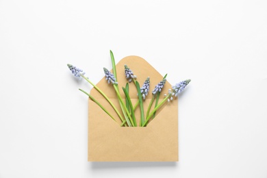 Envelope with beautiful spring muscari flowers on light background, top view