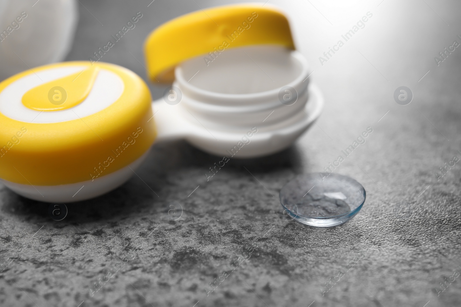 Photo of Contact lens and container on table, closeup