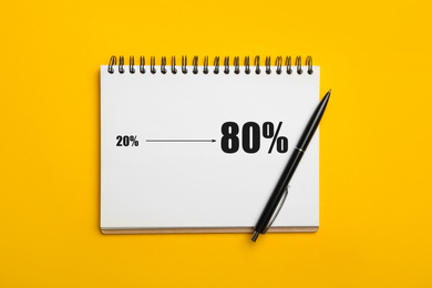 Pareto principle concept. Notebook with 80/20 rule representation on yellow background, top view