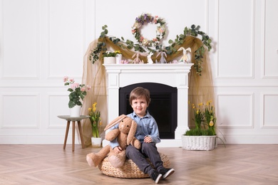 Photo of Cute little boy with toy bunny in decorated room. Beautiful Easter photo zone