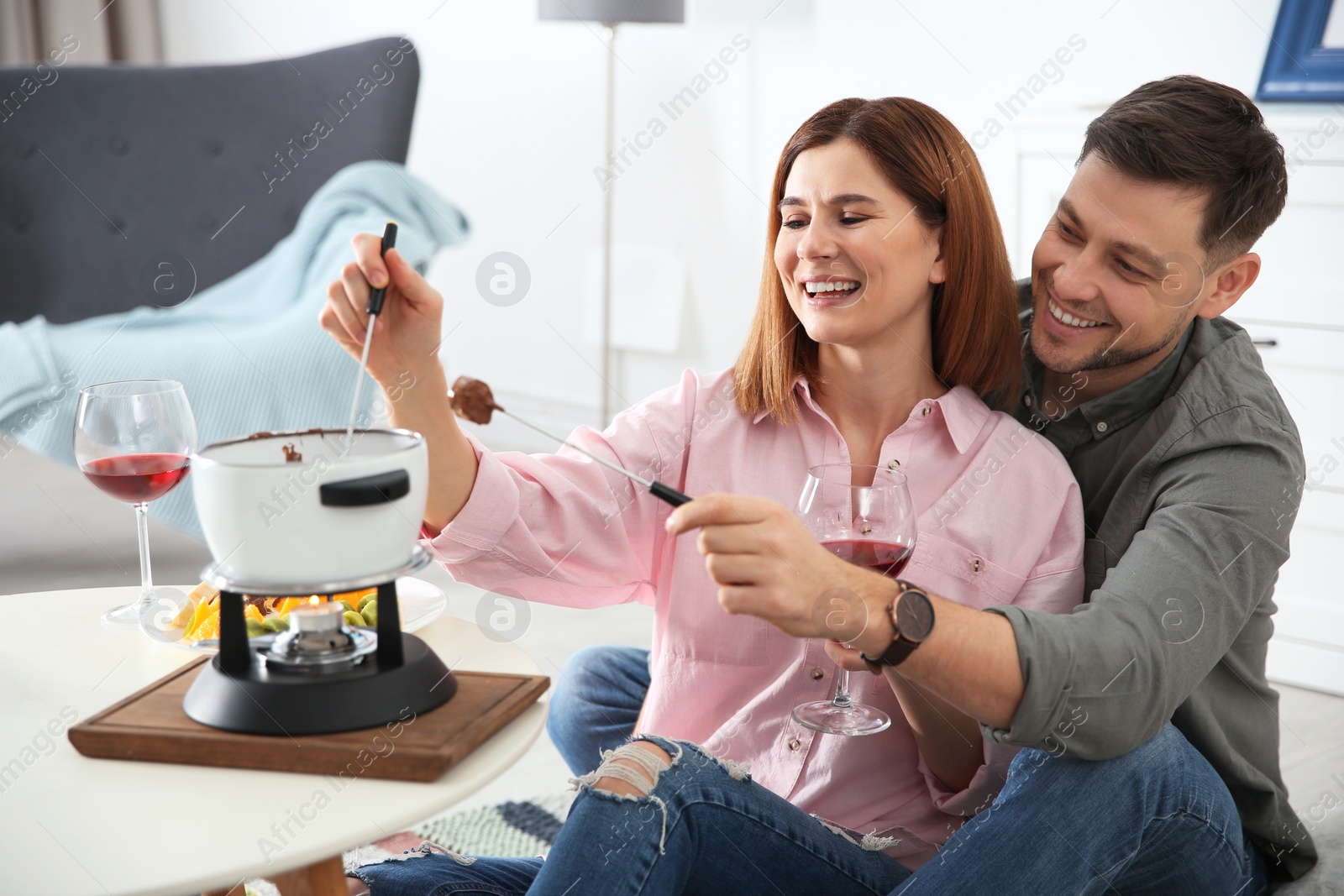 Photo of Happy couple enjoying fondue dinner at home