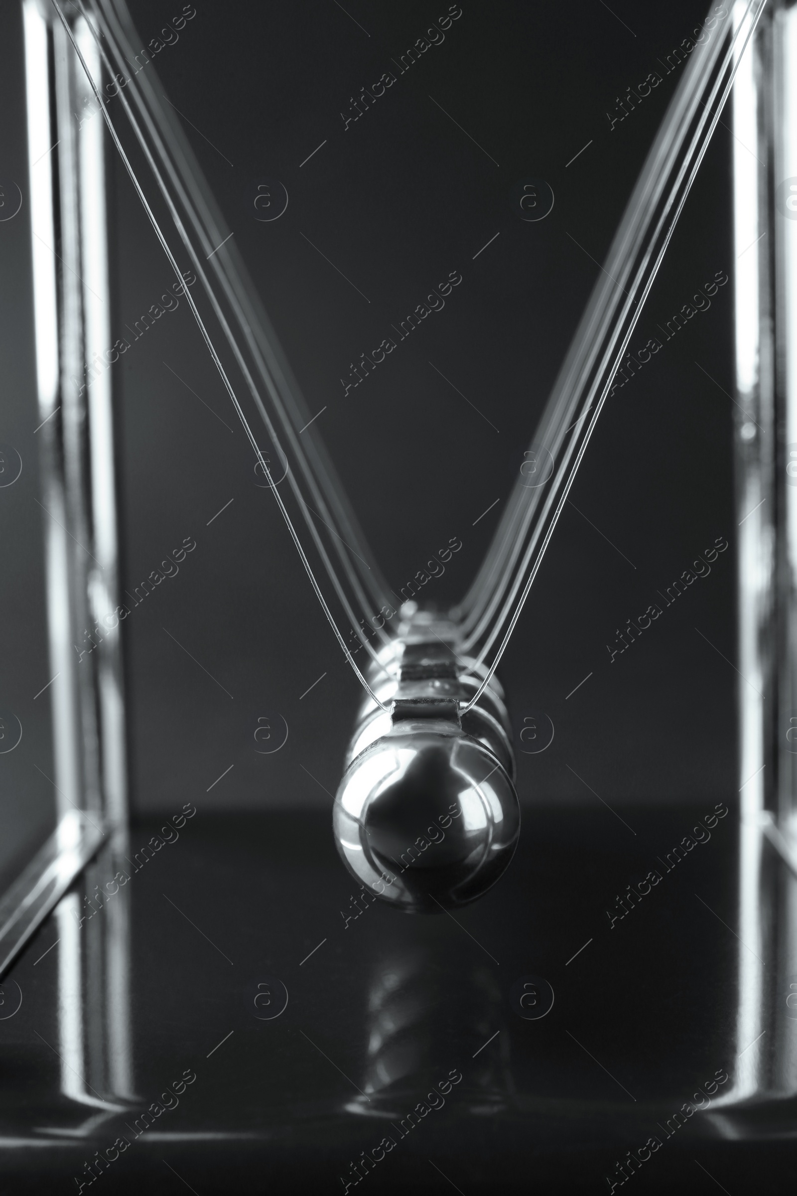 Photo of Newton's cradle on dark background, closeup. Physics law of energy conservation