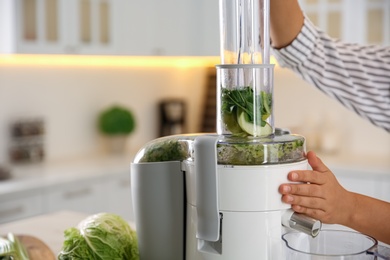 Photo of Young woman making tasty fresh juice in kitchen, closeup