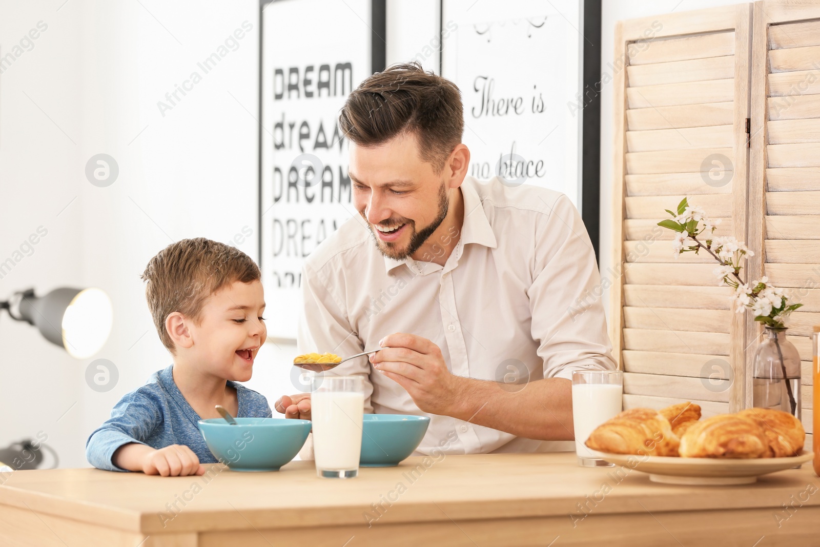 Photo of Father and son having breakfast with milk at table