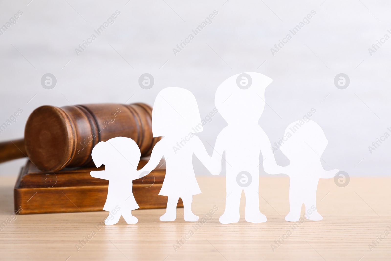 Photo of Figure in shape of people and gavel on wooden table. Family law concept