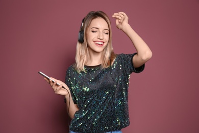 Photo of Young woman listening to music on mobile phone against color background