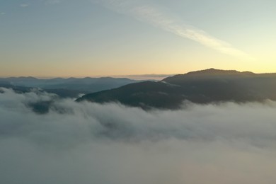 Photo of Aerial view of beautiful mountains covered with fluffy clouds in morning