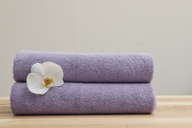 Stack of fresh towels with flower on table