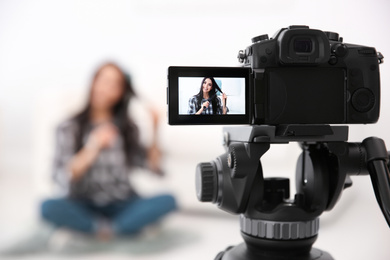 Photo of Young blogger recording video at cafe, focus on camera screen