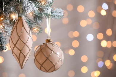 Photo of Christmas tree decorated with holiday baubles  against blurred lights, closeup. Space for text