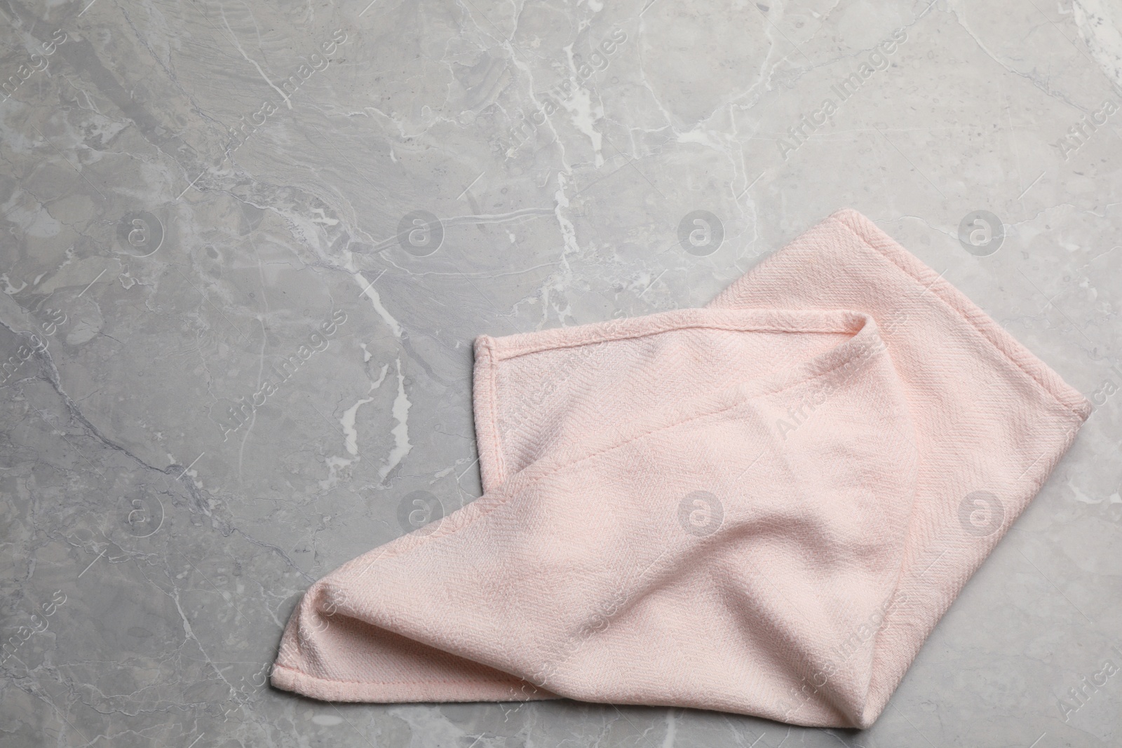 Photo of Pink kitchen towel on grey table, top view. Space for text