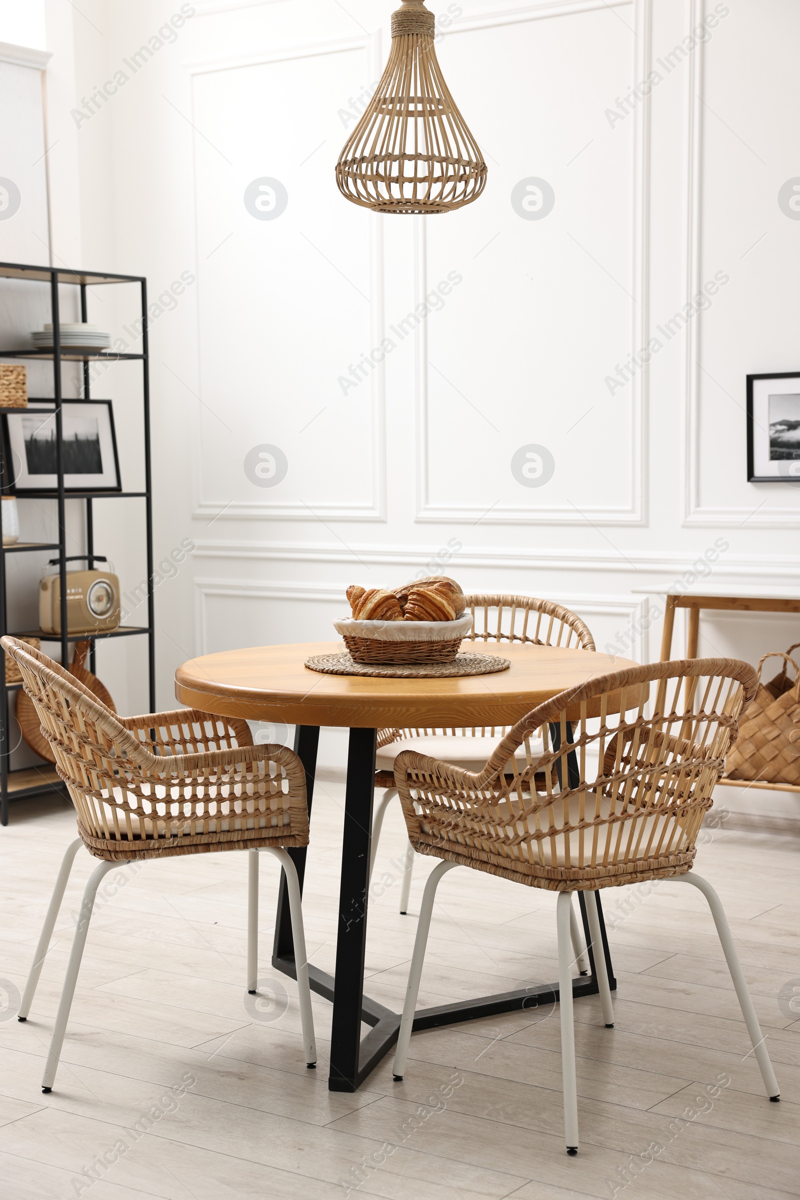 Photo of Dining room interior with wooden table and wicker chairs