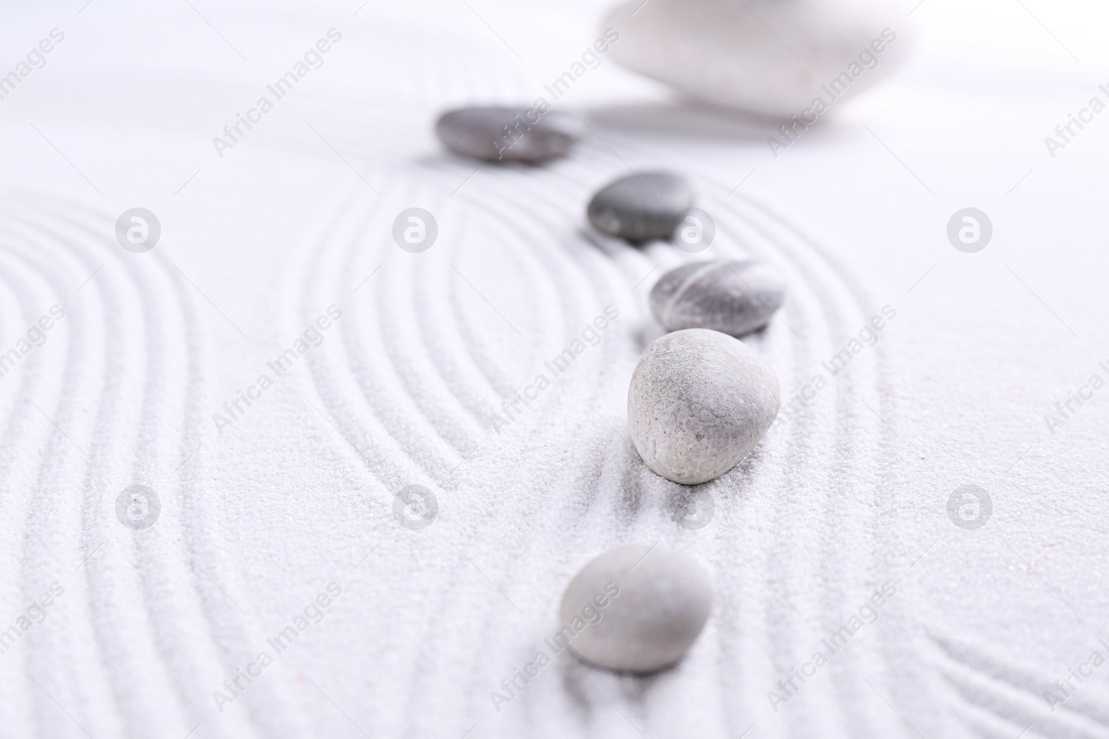 Photo of Zen garden stones on white sand with pattern, space for text