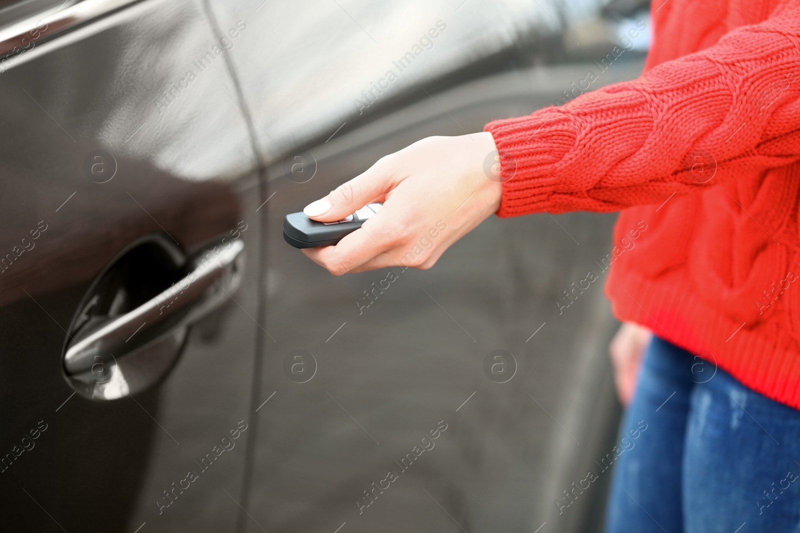 Photo of Closeup view of woman opening car door with remote key