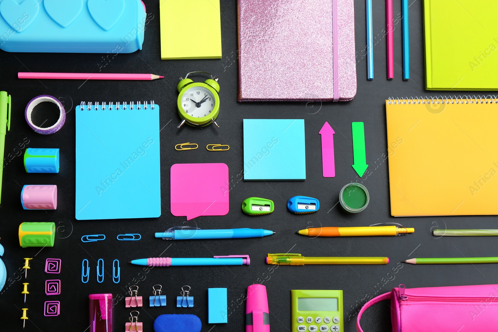 Photo of Different bright school stationery on black background, flat lay