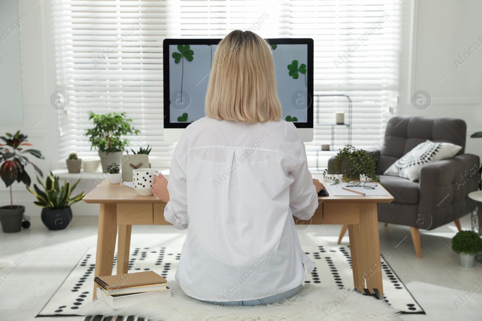 Photo of Woman working at table in light room, back view. Home office