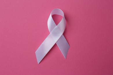 Photo of White awareness ribbon on pink background, top view