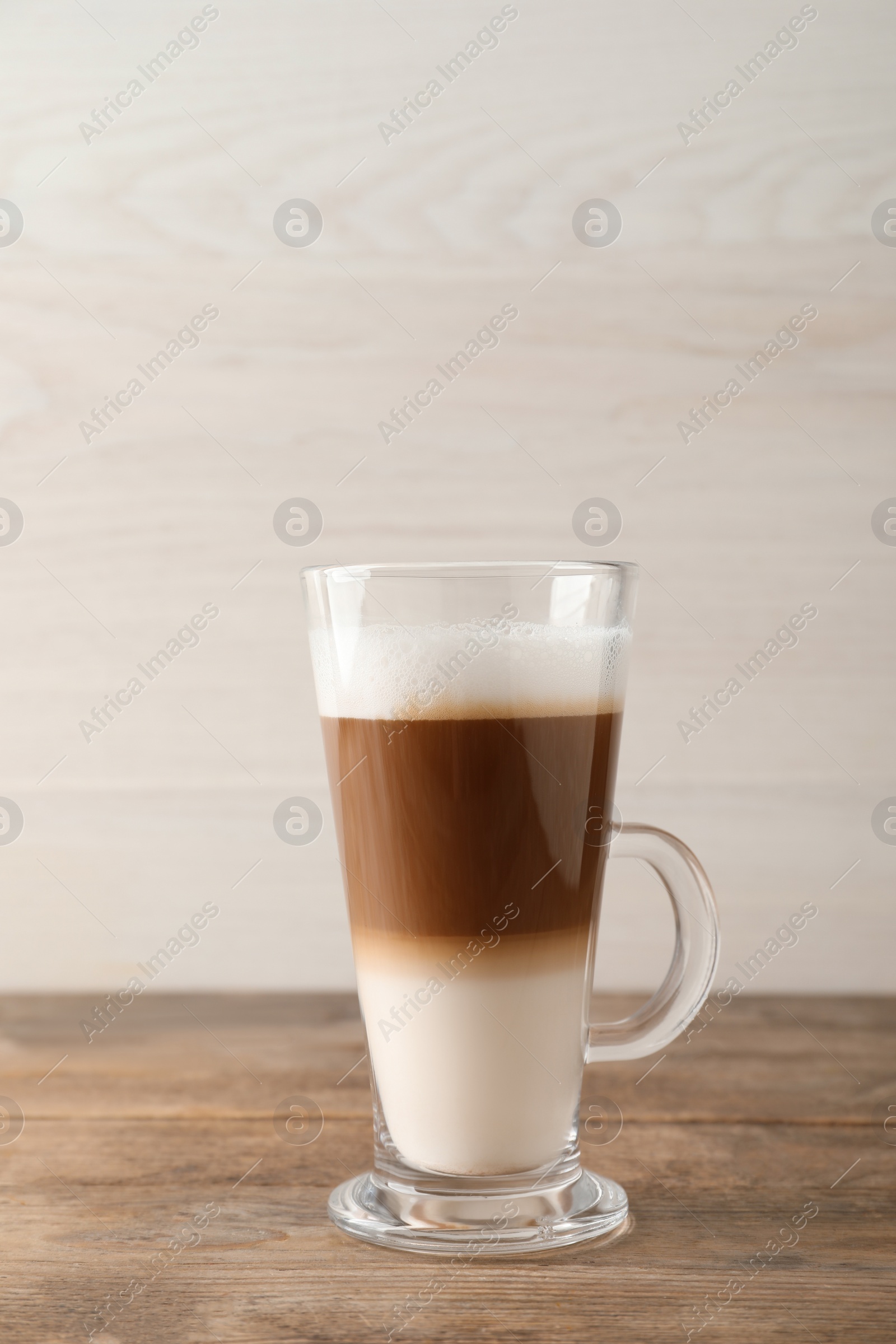 Photo of Hot coffee with milk in glass cup on wooden table