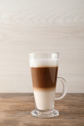 Photo of Hot coffee with milk in glass cup on wooden table