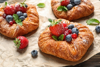 Photo of Fresh delicious puff pastry with sweet berries on parchment
