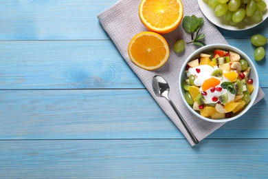 Photo of Delicious fruit salad served on light blue wooden table, flat lay. Space for text