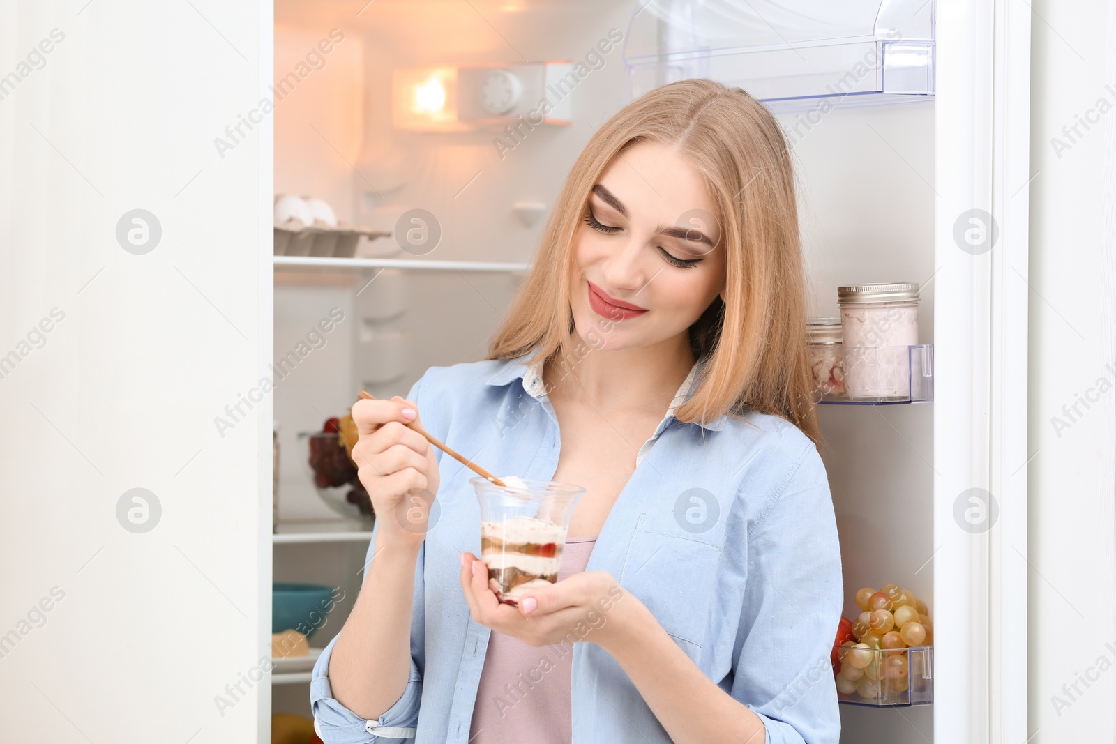 Photo of Young woman with yogurt in kitchen