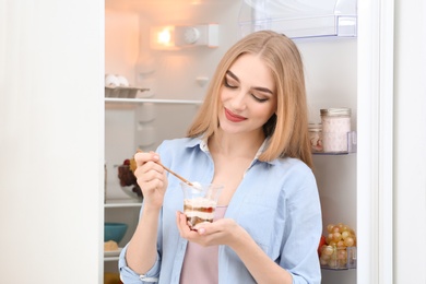 Photo of Young woman with yogurt in kitchen