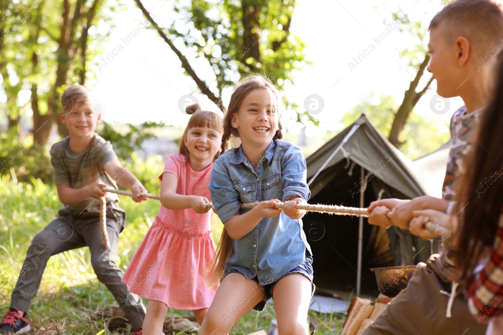 Photo of Little children pulling rope outdoors. Summer camp