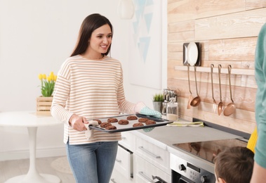 Photo of Woman treating her family with oven baked cookies at home