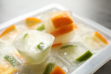 Photo of Ice cube tray with frozen fruits on table, closeup
