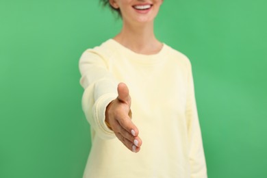 Photo of Woman welcoming and offering handshake on green background, closeup
