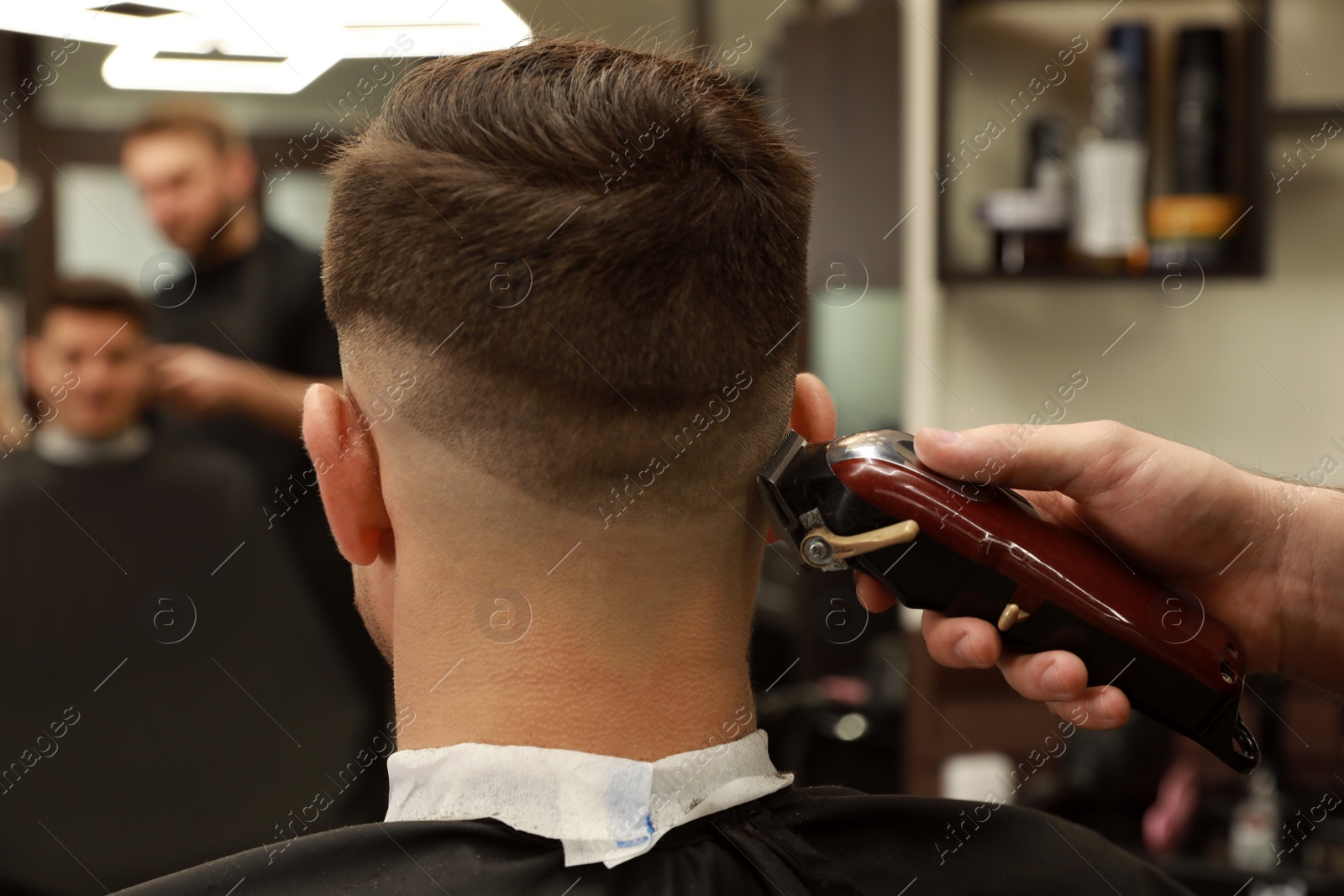 Photo of Professional hairdresser making stylish haircut in salon, back view