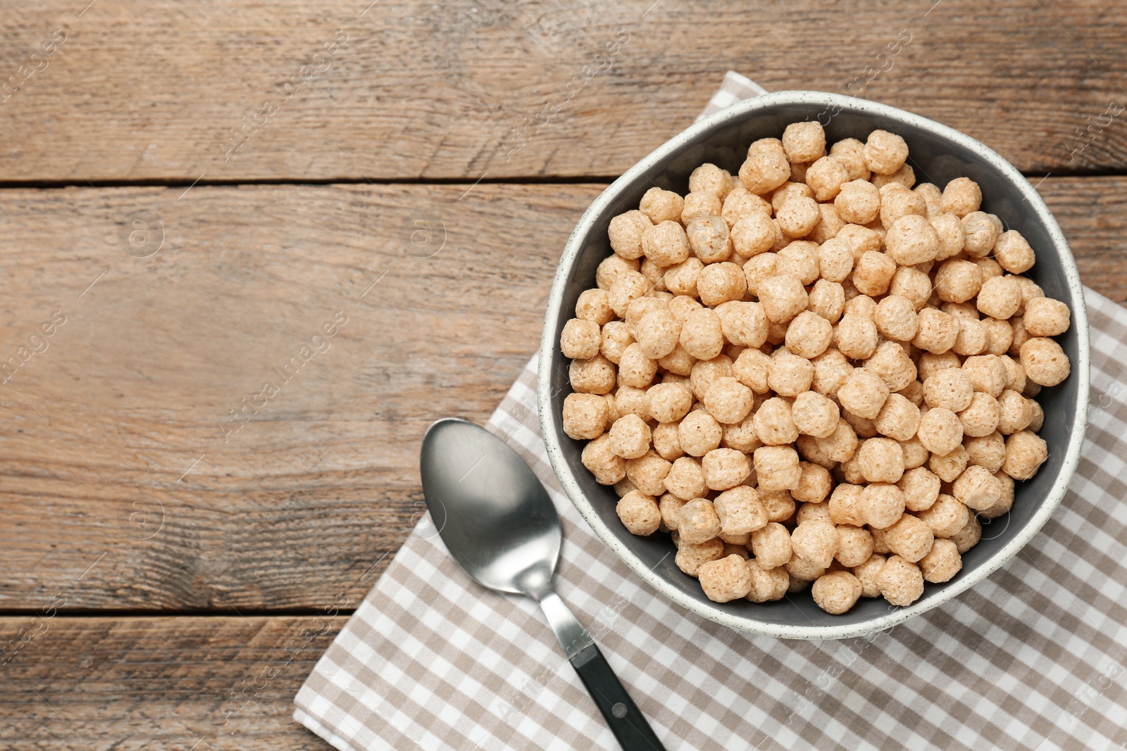 Photo of Bowl of sweet crispy corn balls on wooden table, flat lay with space for text. Breakfast cereal