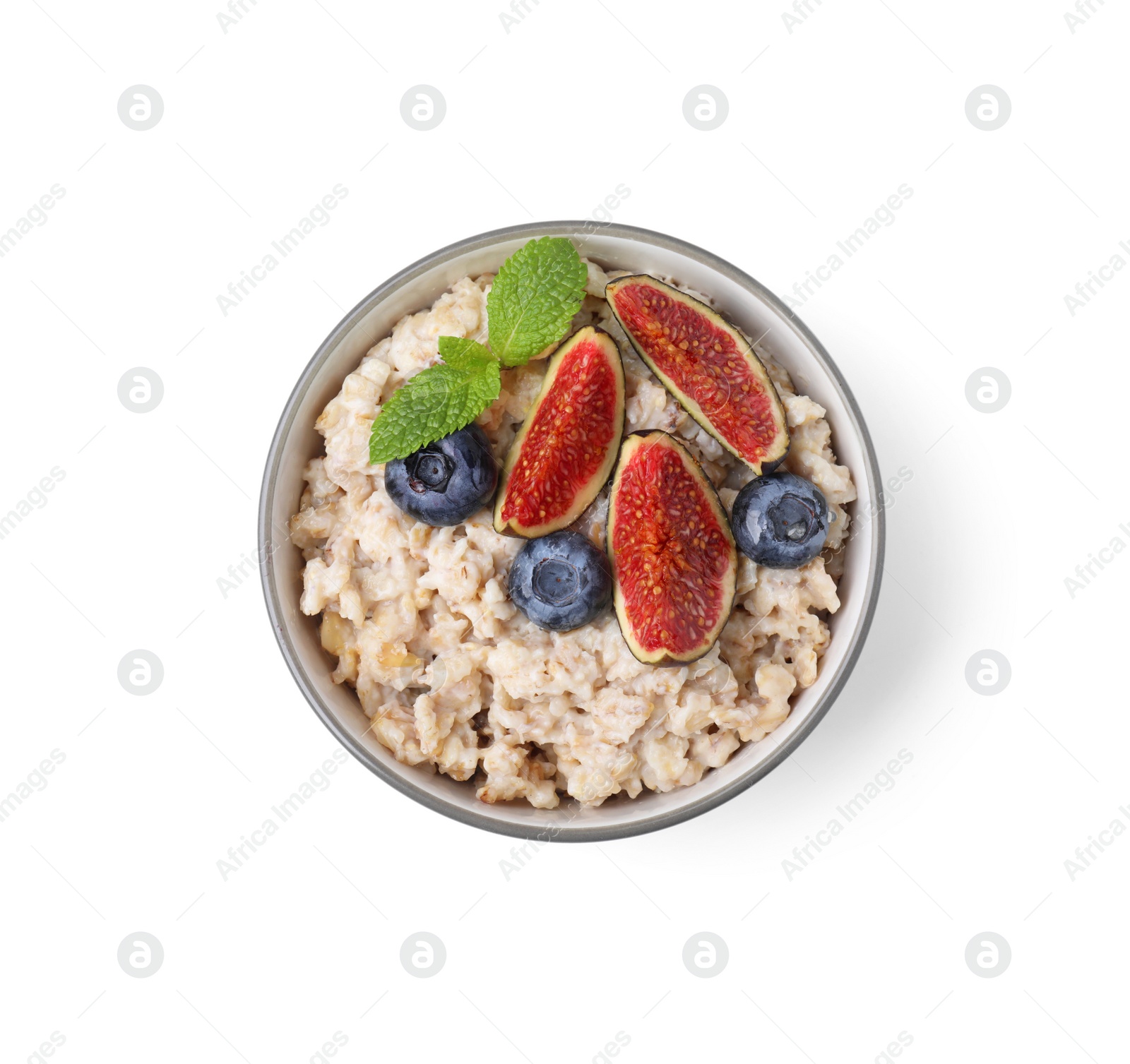 Photo of Bowl of oatmeal with blueberries, mint and fig pieces isolated on white, top view