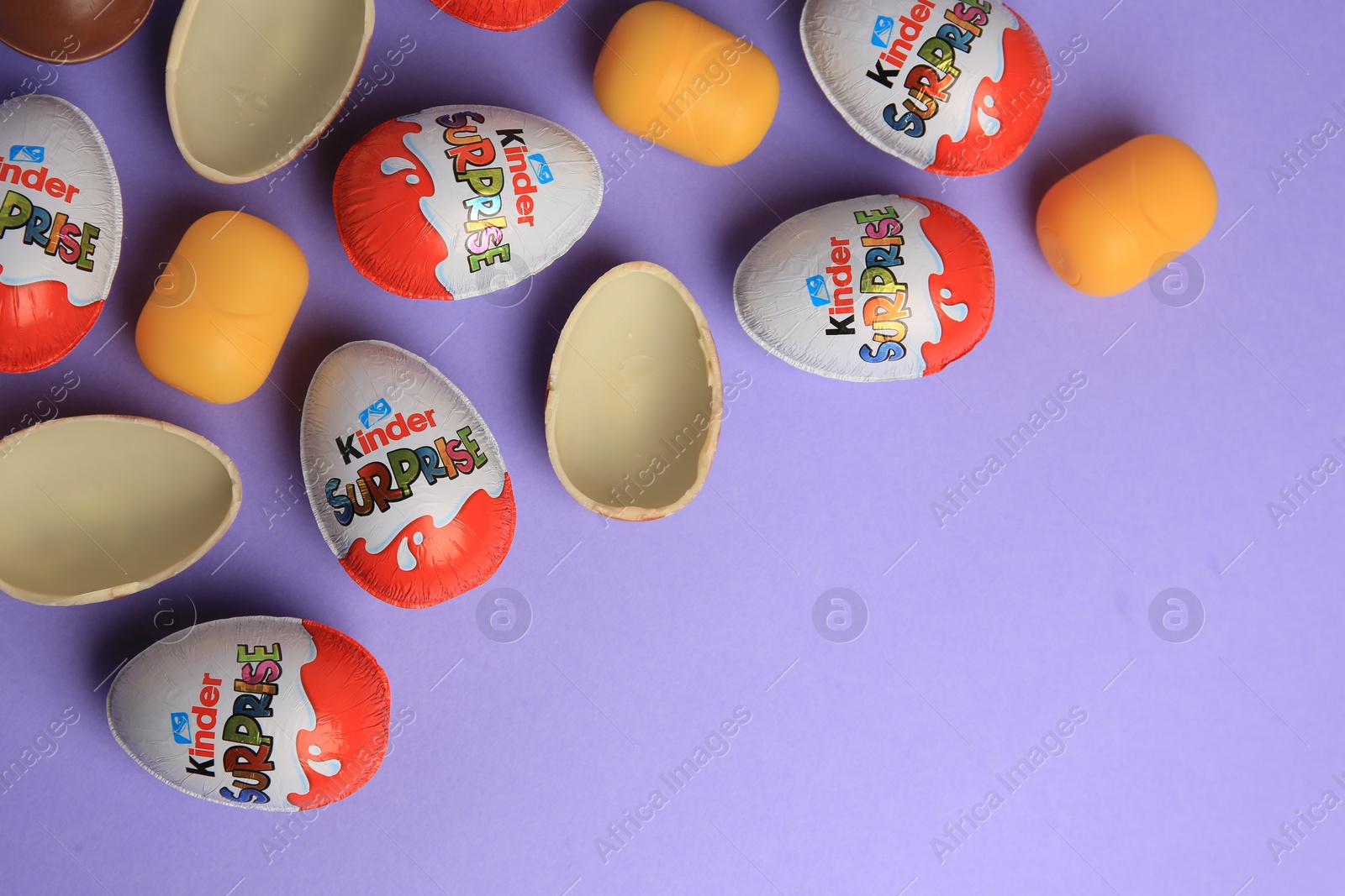 Photo of Sveti Vlas, Bulgaria - June 29, 2023: Kinder Surprise Eggs and plastic capsules on violet background, flat lay. Space for text