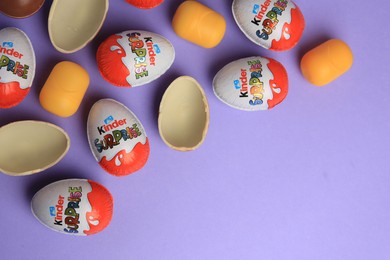 Sveti Vlas, Bulgaria - June 29, 2023: Kinder Surprise Eggs and plastic capsules on violet background, flat lay. Space for text