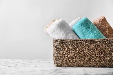 Basket with clean towels on table against light background