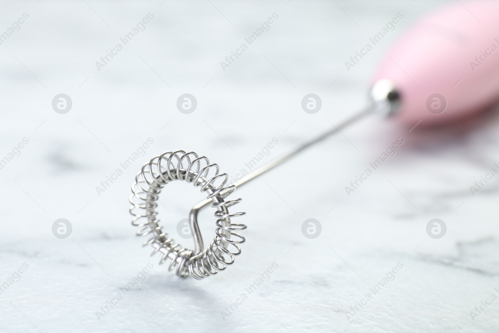 Photo of Pink milk frother wand on white marble table, closeup