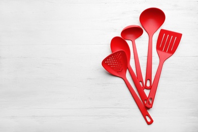 Photo of Different kitchen utensils on wooden background, top view with space for text