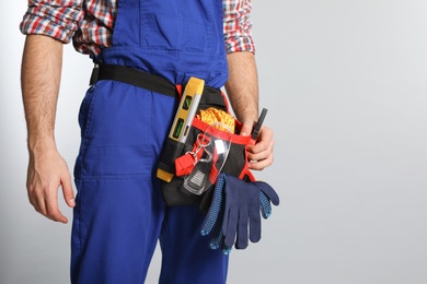 Photo of Construction worker with tool belt on light background, closeup. Space for text