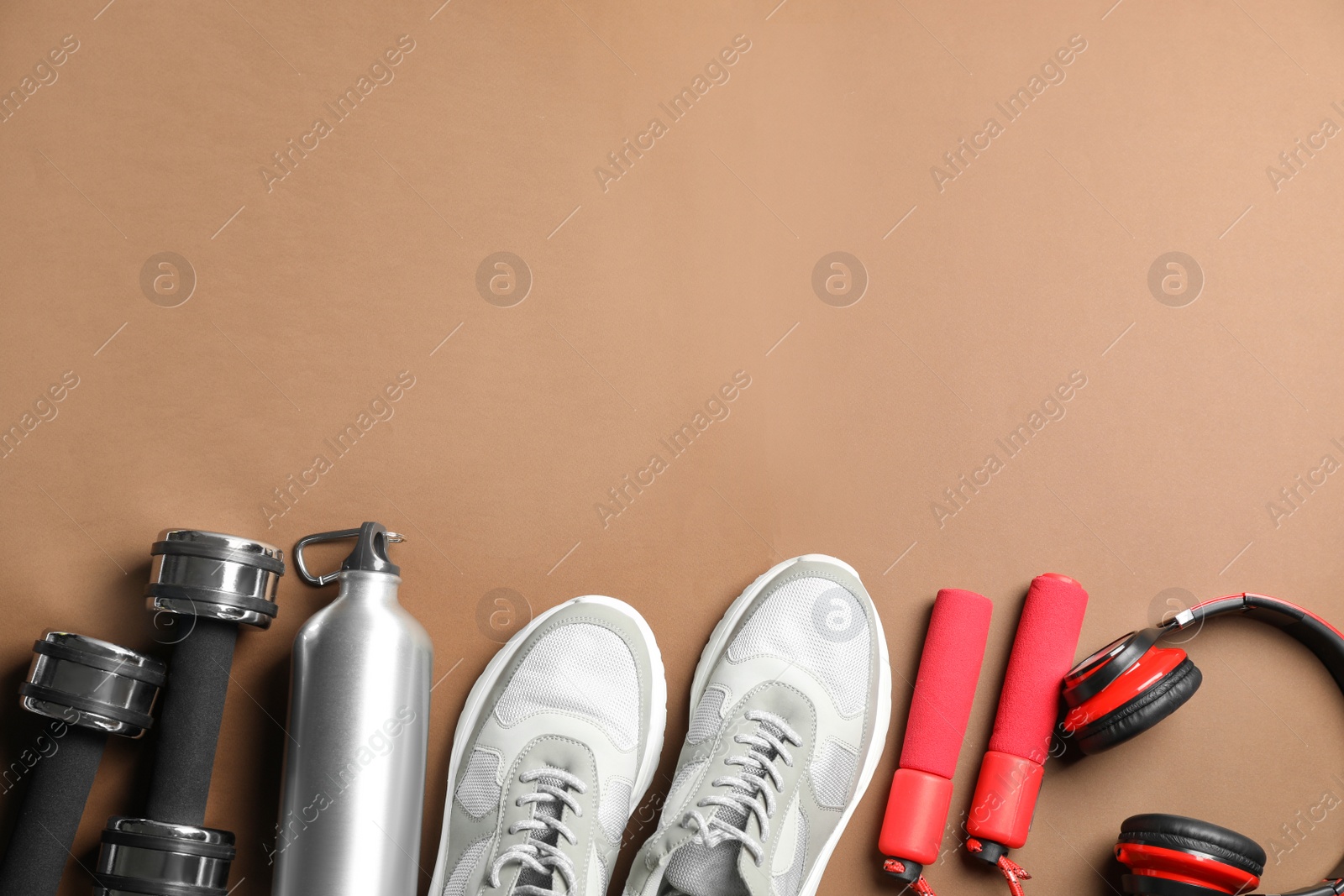 Photo of Flat lay composition with fitness equipment on brown background, space for text