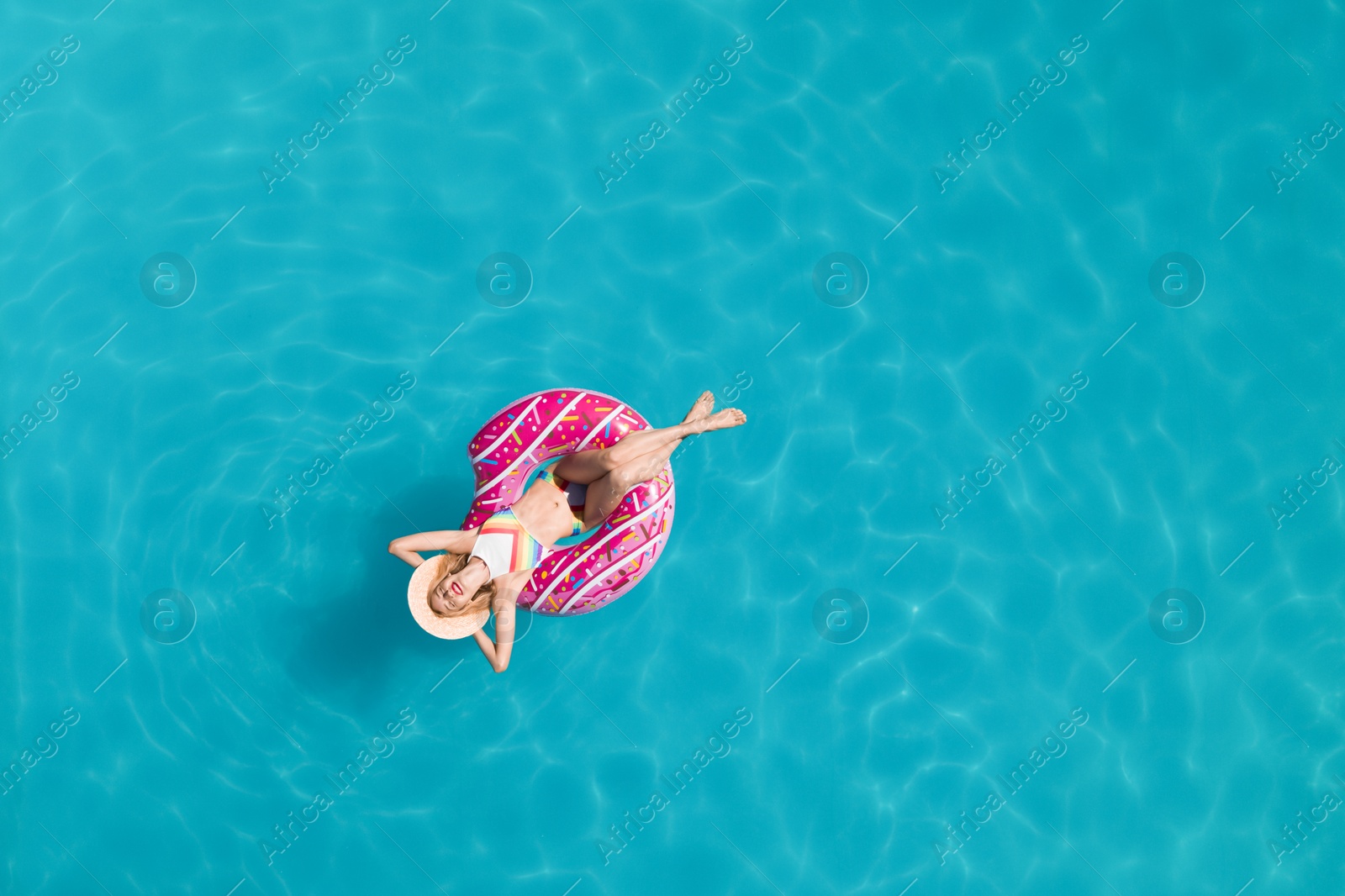 Image of Young happy woman with inflatable ring in swimming pool, top view. Summer vacation